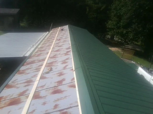 Old rusted panels beside newly installed green metal roofing — Wind Damage Roof Repair by Roofing Brothers in Dousman