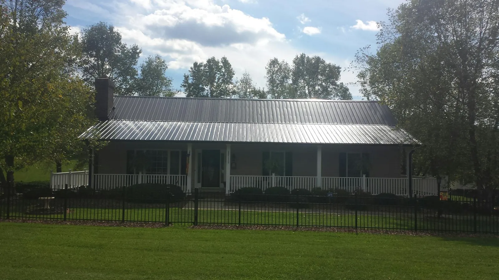 Gray metal roof on a brick ranch with a full width front porch — Gutter Guard Installation work by our crew in Dousman
