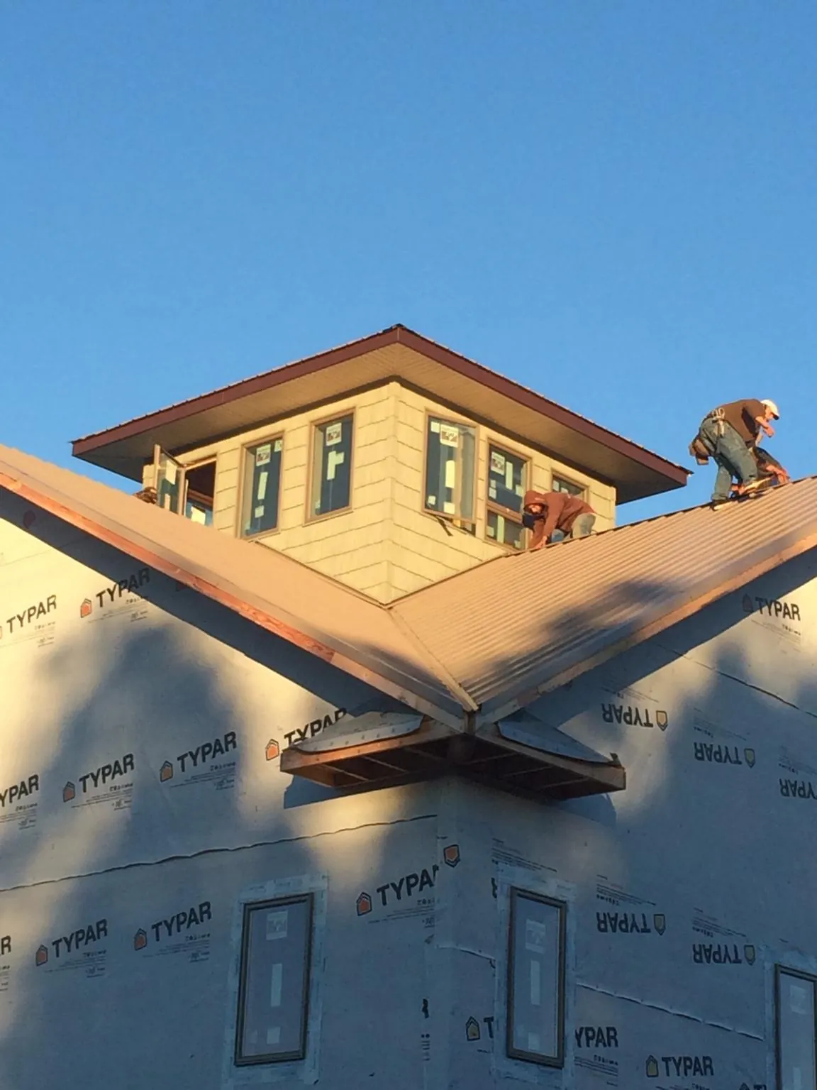 Roofers working around a rooftop cupola on a new metal roof at sunset — Roof Waterproofing in Dousman by Roofing Brothers